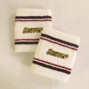 Tennis style white wristbands with brown and red stripes and with custom logo embroidery